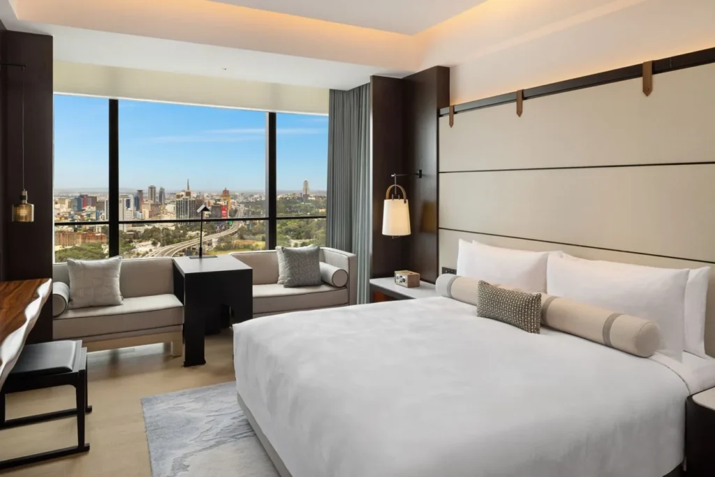 A hotel bedroom with a seating area beside the window.
