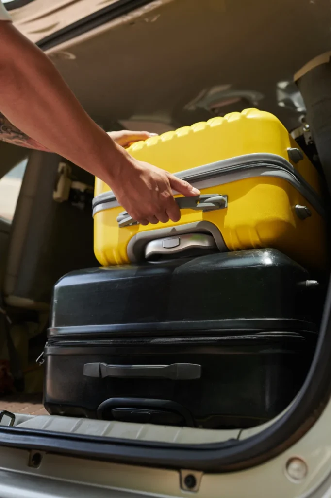 A suitcase being loaded into the luggage space of a vehicle.