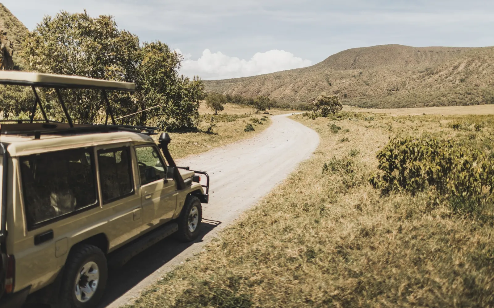 A safari vehicle travelling along a winding Kenyan track.